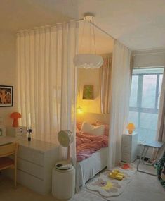 a bedroom with a bed, desk and window in the corner that has sheer curtains on it