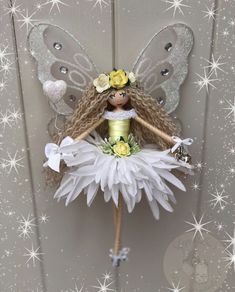 a fairy doll hanging from the side of a door with flowers on her head and wings