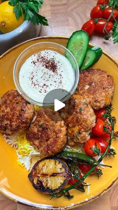 a yellow plate topped with meatballs and veggies next to a bowl of ranch dressing