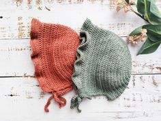 two crocheted hats sitting next to each other on top of a wooden table