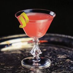 a pink cocktail with a lemon wedge on the rim and garnished in sugar