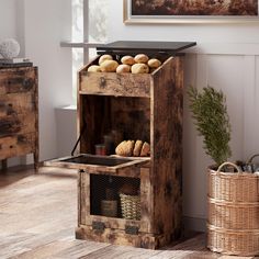 a wooden crate with bread in it sitting on the floor next to a basket and table