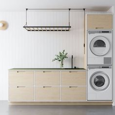 a washer and dryer in a white room with wooden cabinetry on the wall