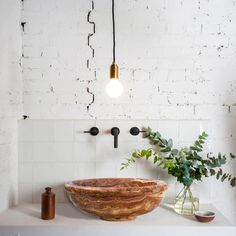 a bowl shaped sink sitting on top of a counter next to a vase with flowers