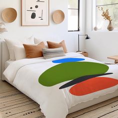 a bed with white sheets and colorful artwork on the wall above it in a bedroom