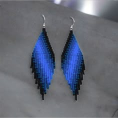 two pairs of earrings with blue and black beads on them, one is shaped like an angel's wing