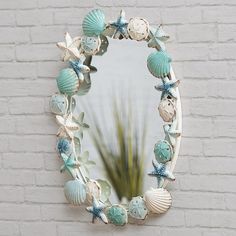 there is a mirror with shells on it and a plant in the corner next to it