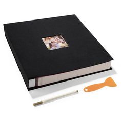 an open book with a photo on it next to a pair of orange handled utensils