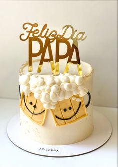 a white cake with gold letters and smiley faces on top that says felice da paa