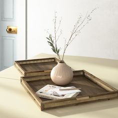 a white vase sitting on top of a wooden tray next to a book and magazine