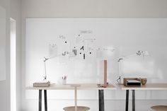 two desks with different types of lamps on them in front of a white wall