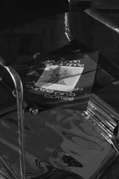 a black and white photo of a book sitting on a metal chair with the cover pulled down