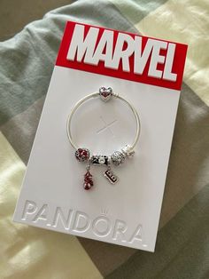 a bracelet with charms on it sitting on top of a bed next to a book