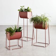 two metal planters with plants in them sitting on the floor next to each other