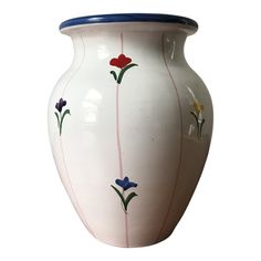 a white vase with flowers painted on the side and blue trim around the top, sitting against a white background