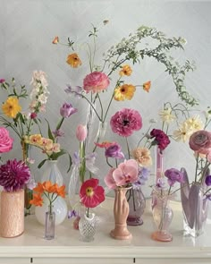 there are many different vases with flowers in them on the table next to each other