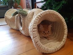 a cat is sitting in a crocheted tunnel on the floor next to a christmas tree