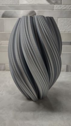 a gray vase sitting on top of a table next to a white tile countertop