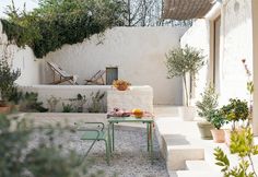 an outdoor patio with tables, chairs and potted plants on the side of it