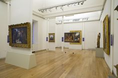 an art gallery with paintings on the wall and wooden flooring in front of them