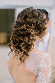 the back of a bride's dress with her hair pulled up in a low bun