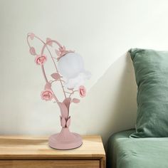 a pink vase with flowers in it sitting on a nightstand next to a green pillow