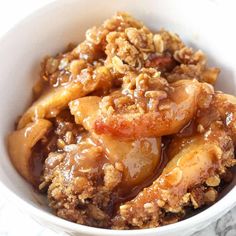 a close up of a bowl of food with apple slices and crumbled topping