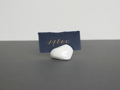 a small white object sitting on top of a table next to a blue cloth name tag