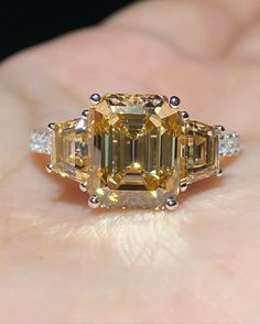 a fancy yellow diamond ring on someone's hand