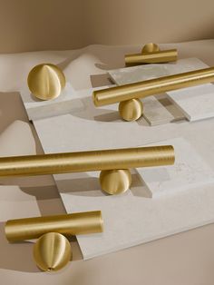 three gold handles and two knobs sitting on top of each other in front of a beige background