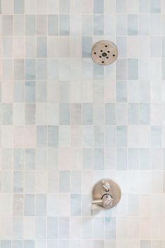 a shower head and hand held shower faucet in a tiled bathroom wall with blue tiles