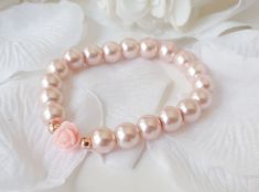 a close up of a bracelet on a white cloth with flowers in the back ground