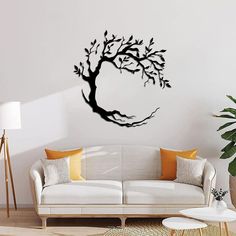 a living room with a white couch and black tree wall decal