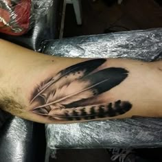 a man's arm with a black and white feather tattoo on it