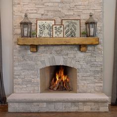 a stone fireplace with candles and pictures on the mantle