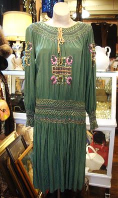 "This is a vintage embroidered and smocked Hungarian peasant dress from the 1920's or early 1930's.  It's green silk, with multi-color embroidery and smocking, all hand done.  It has a scoop neckline, and there are a couple of small spots in front at the hem that I have not tried to remove. (see photos).  The smocked hip band is flexible, so the dress just pops over your head.   A classic boho look from back in the day!  Comes from a smoke free home. Measurements: Bust: up to 46\"   Hip: 38\"   Sleeve Length from Neckline to Sleeve Edge:  28\"   Length:  44.5\" Please ask me any questions you may have before buying as this is a final sale. Please know your measurements and allow for movement.  I ship within 3 business days of cleared payment, usually sooner. If you need something quickly, Bohemian Dresses With Smocked Cuffs, Green Embroidered Vintage Dress, Vintage Green Embroidered Dress, Vintage Embroidered Green Dress, Vintage Embroidered Fall Dresses, Bohemian Daywear Dress With Smocked Cuffs, Fitted Smock Peasant Dress, High Waist Dress Pattern, 1920s Day Dress