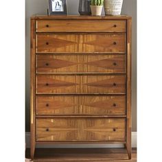 a wooden chest of drawers sitting on top of a hard wood floor next to a potted plant