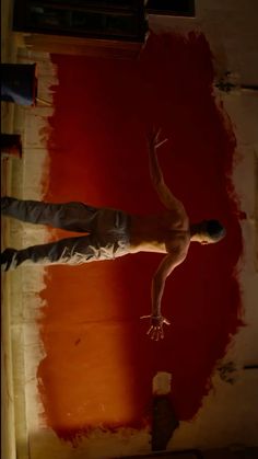 a man standing in the middle of a room with red paint on the walls and floor