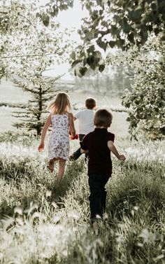 two young children are walking through the grass