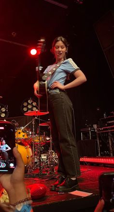 a woman standing on top of a stage holding a cell phone in front of her