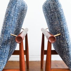 two wooden chairs with blue upholstered cushions on top of each chair and one has a wood leg rest