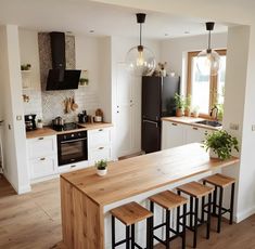 a kitchen with white cabinets and wooden counter tops next to a black refrigerator freezer