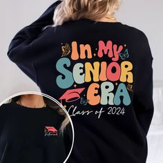 a woman wearing a black sweatshirt with the words in my senior era printed on it