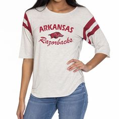 Elevate the style of your game day tee with this Arkansas Razorbacks Sabrina Jersey T-shirt. It features the team name and logo accentuated by contrast-color side stitching and sleeve stripes. A rounded hem gives this Arkansas Razorbacks shirt a more comfortable fit and feel. Razorback Shirt, Arkansas Razorbacks, Team Name, Striped Sleeve, Team Names, The Team, Jersey T Shirt, Arkansas, Game Day