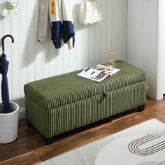 a green bench with an umbrella hanging from it's hooks and clothes on the wall