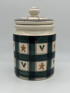 a green and white plaid cookie jar with a teddy bear on the lid, sitting against a gray background