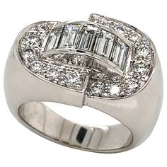 The ring we present is a stunning Art Deco piece in 18 K white gold, designed to capture the essence of the era's iconic style. With a solid weight of 16.33 grams, this ring embodies luxury and superior quality. This ring is adorned with five baguette-cut white diamonds, each meticulously selected for its dazzling clarity and brilliance. The baguette cut gives these diamonds a refined, sophisticated look, adding a modern touch to the classic Art Deco aesthetic. In addition, sixteen round-cut whi Art Deco Aesthetic, Round Diamond Ring, Baguette Cut Diamond, Deco Ring, Iconic Style, Art Deco Diamond, Domed Ring, Baguette Cut, Art Deco Ring