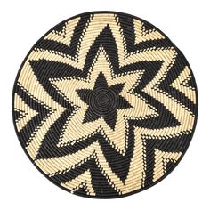 a black and white circular basket with an intricate design on the bottom, in front of a