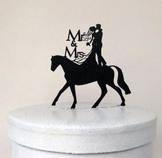 a wedding cake topper with a silhouette of a bride and groom riding a horse