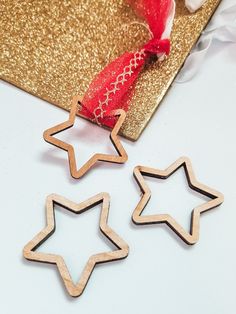 three wooden stars sitting on top of a table next to a red bow and ribbon